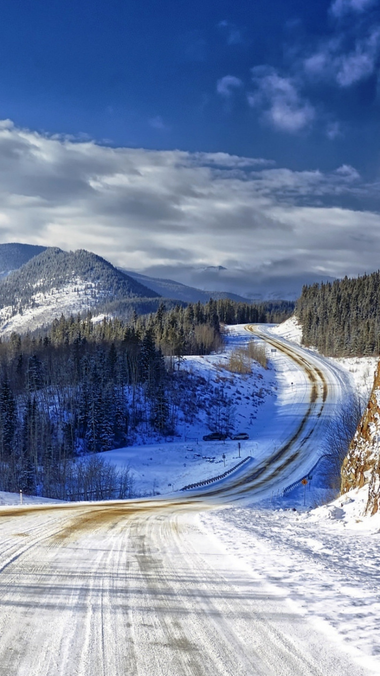 Schneebedeckte Straße in Der Nähe Von Bäumen Und Schneebedeckten Bergen Unter Blauem Himmel Tagsüber. Wallpaper in 750x1334 Resolution