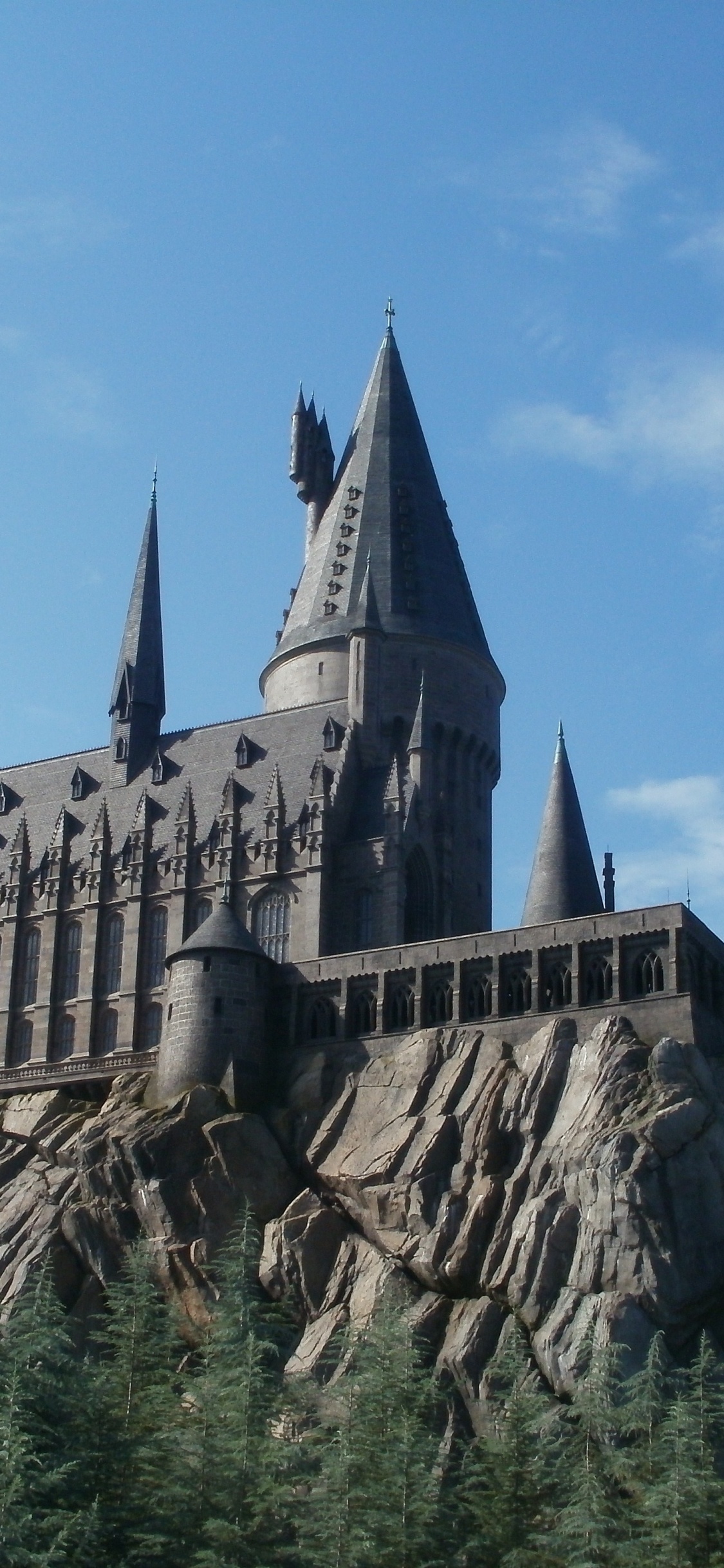 Brown Concrete Castle Near Green Trees Under Blue Sky During Daytime. Wallpaper in 1125x2436 Resolution