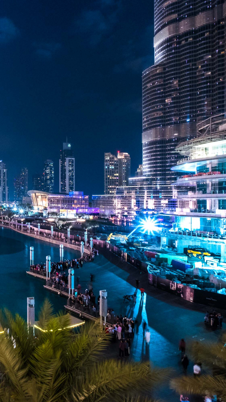Water Fountain Near Green Palm Trees During Night Time. Wallpaper in 750x1334 Resolution