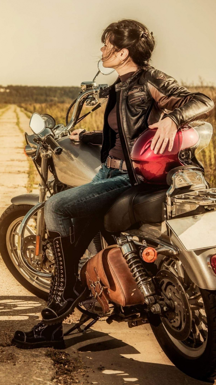 Woman in Black Jacket and Blue Denim Jeans Sitting on Black Motorcycle on Road During Daytime. Wallpaper in 750x1334 Resolution