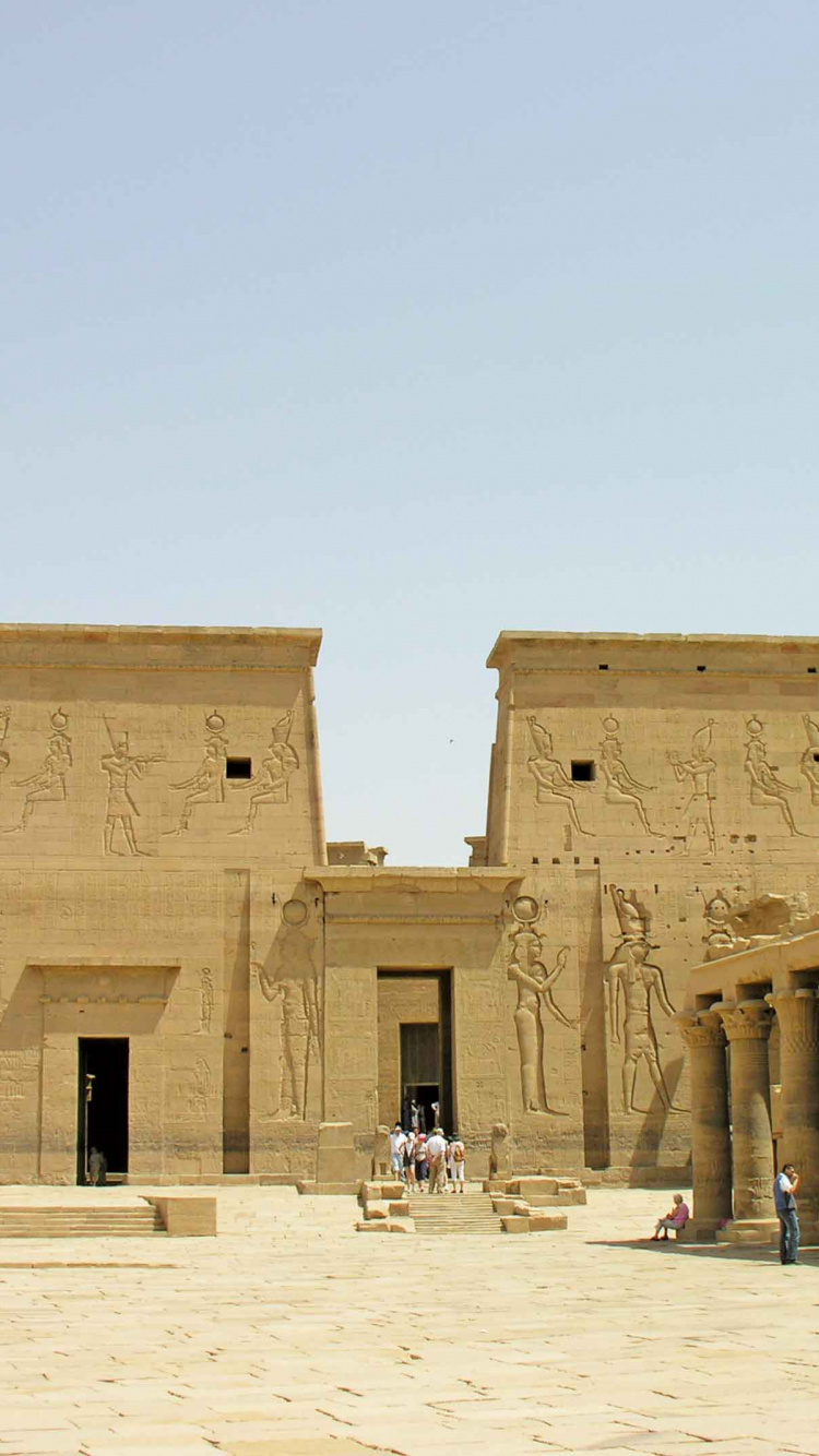 People Walking on White Sand Near Brown Concrete Building During Daytime. Wallpaper in 750x1334 Resolution