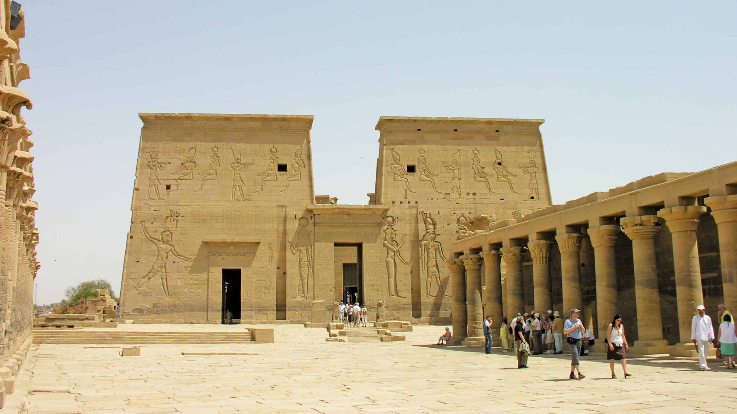 Personnes Marchant Sur du Sable Blanc Près D'un Bâtiment en Béton Brun Pendant la Journée. Wallpaper in 2560x1440 Resolution