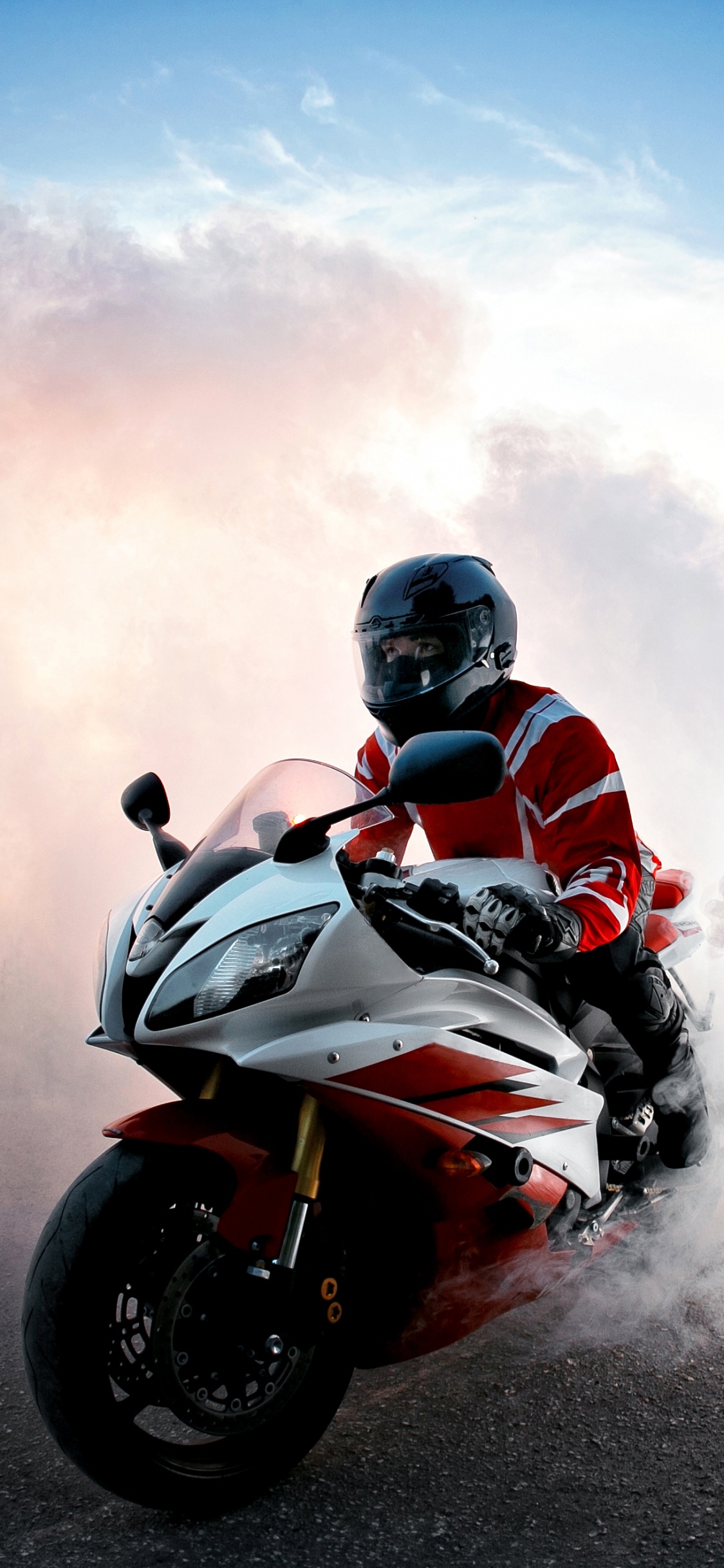 Man in Black Helmet Riding Red Sports Bike. Wallpaper in 1125x2436 Resolution