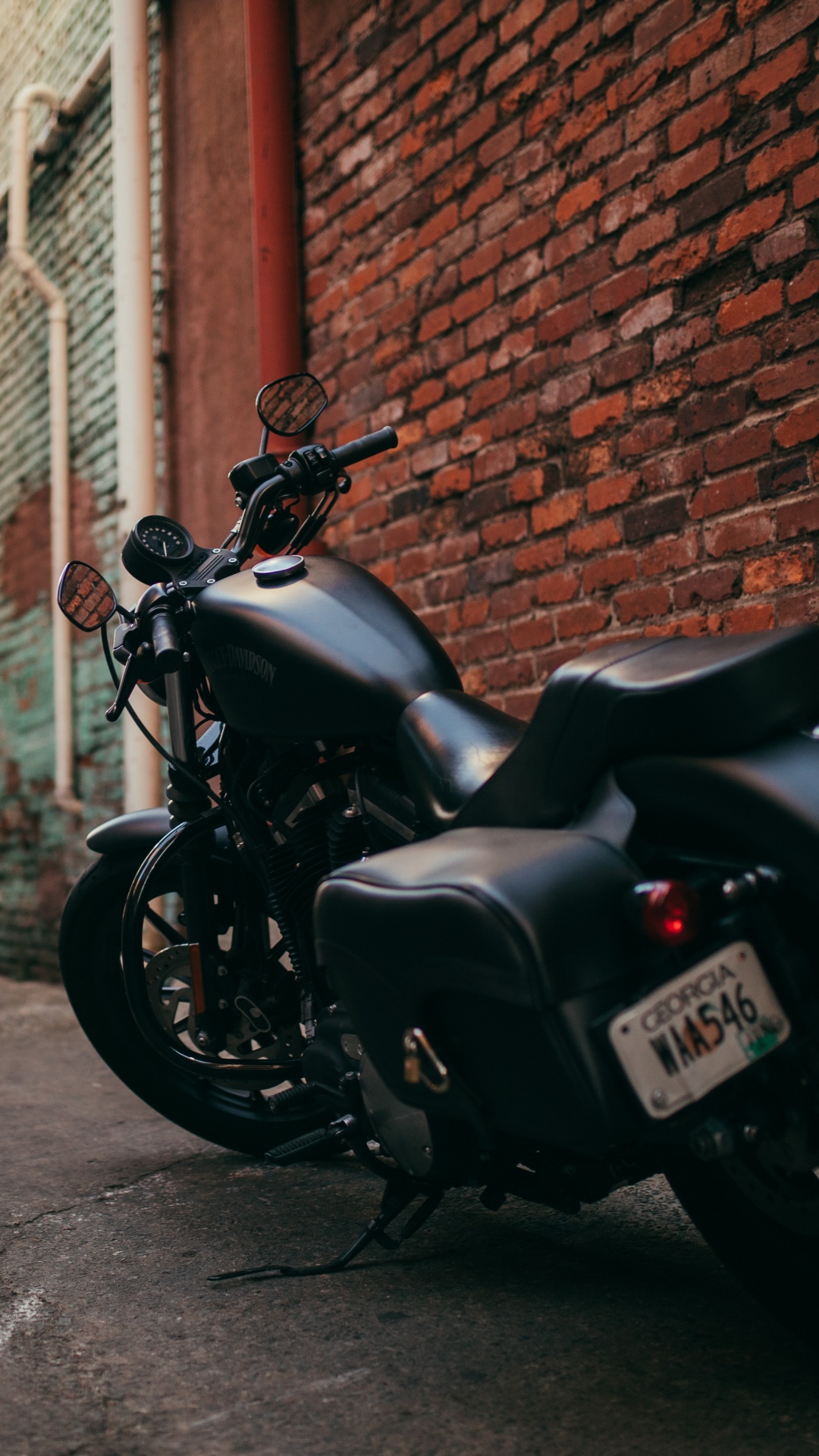 Black Motorcycle Parked Beside Brown Brick Wall. Wallpaper in 1080x1920 Resolution