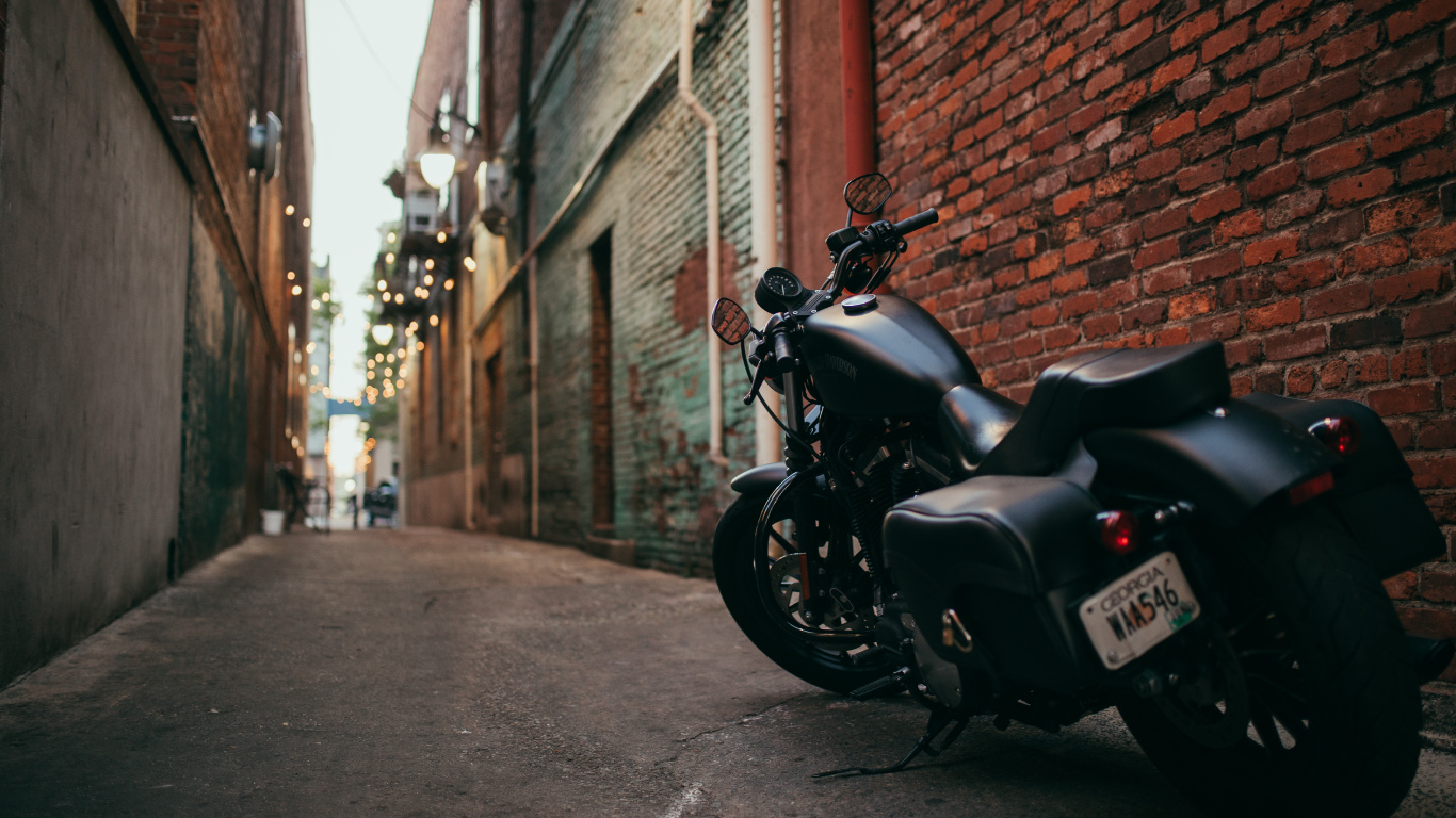Schwarzes Motorrad Neben Brauner Backsteinmauer Geparkt. Wallpaper in 1366x768 Resolution