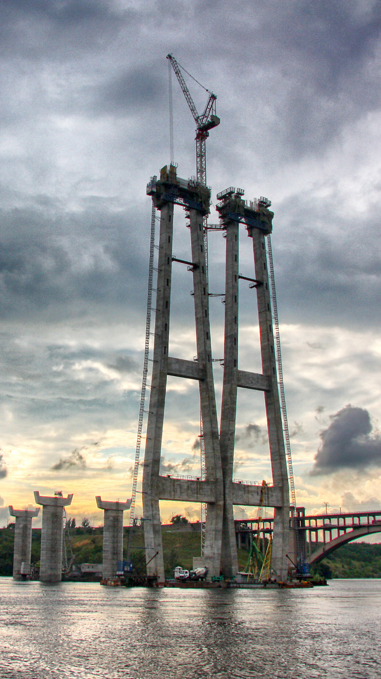 Edificio de Hormigón Marrón Cerca Del Cuerpo de Agua Bajo un Cielo Nublado Durante el Día. Wallpaper in 750x1334 Resolution