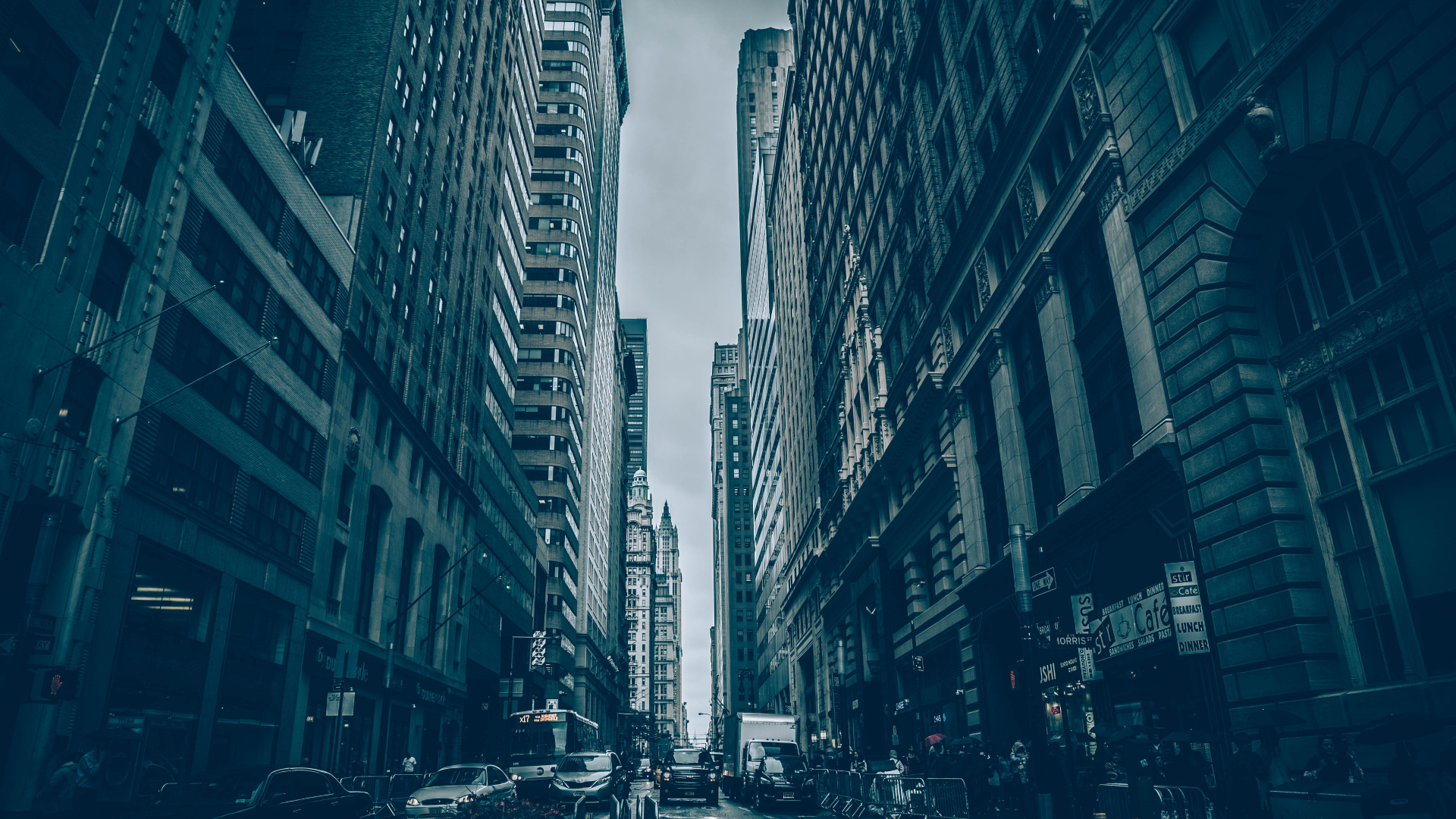 Grayscale Photo of Cars on Road Between High Rise Buildings. Wallpaper in 1920x1080 Resolution