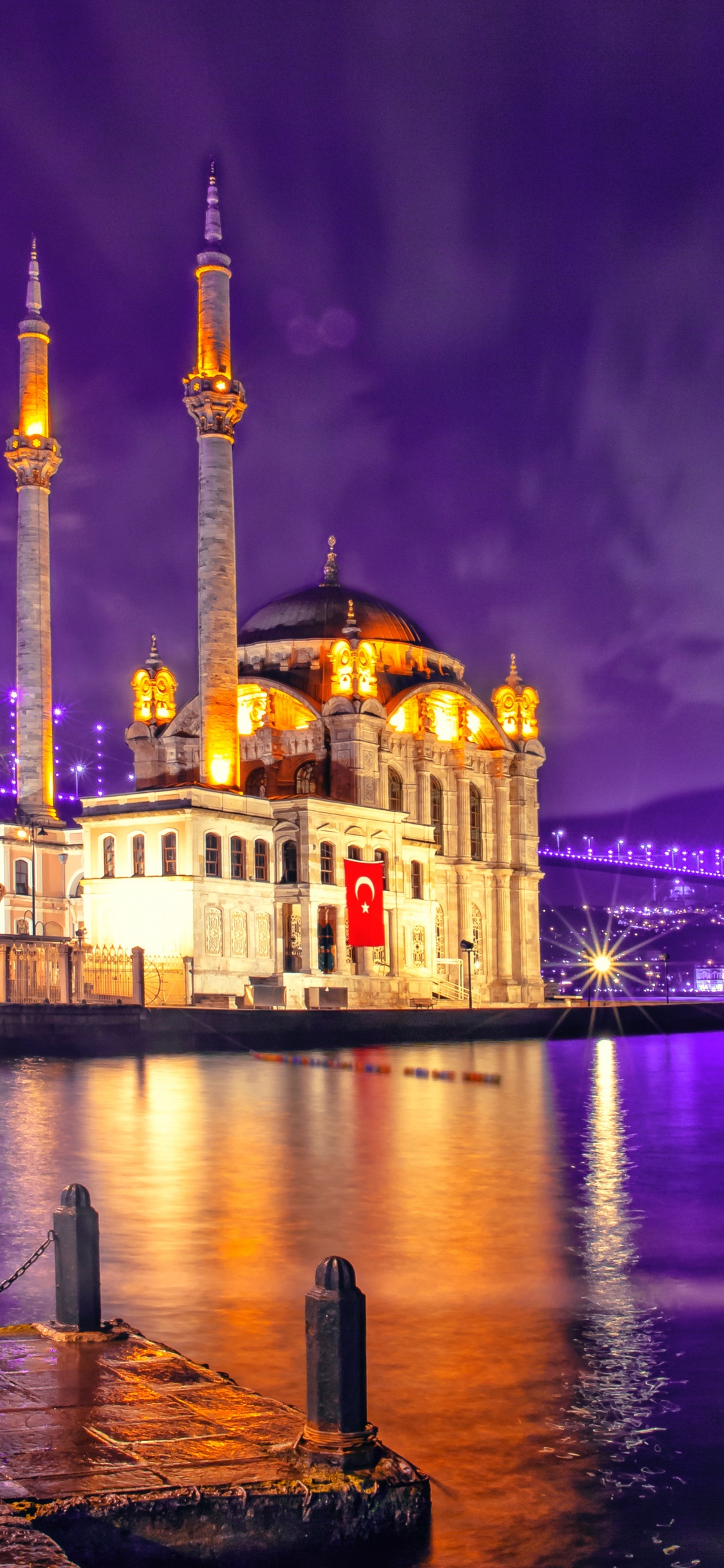 Bâtiment en Béton Brun Près D'un Plan D'eau Pendant la Nuit. Wallpaper in 1125x2436 Resolution