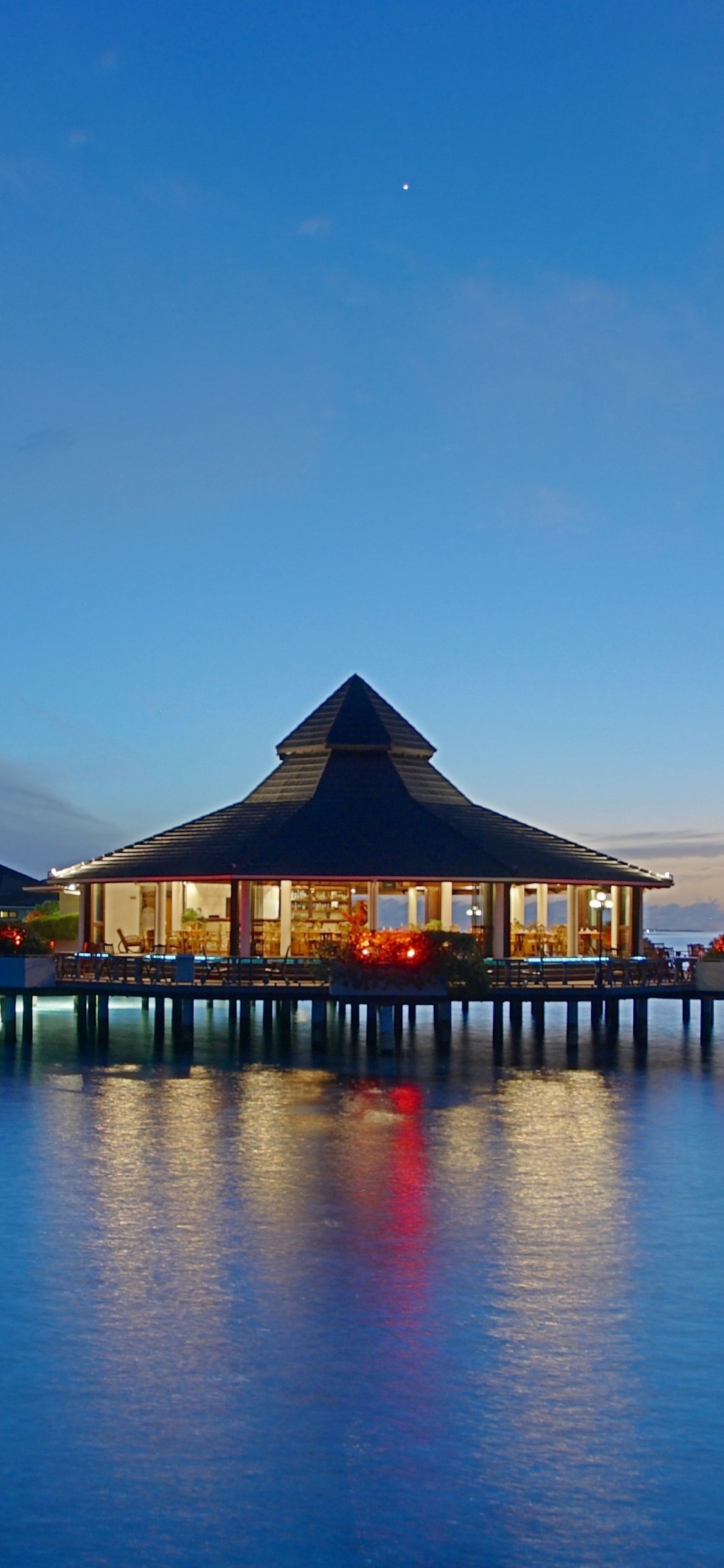 Brown Wooden Gazebo on Body of Water During Night Time. Wallpaper in 1125x2436 Resolution