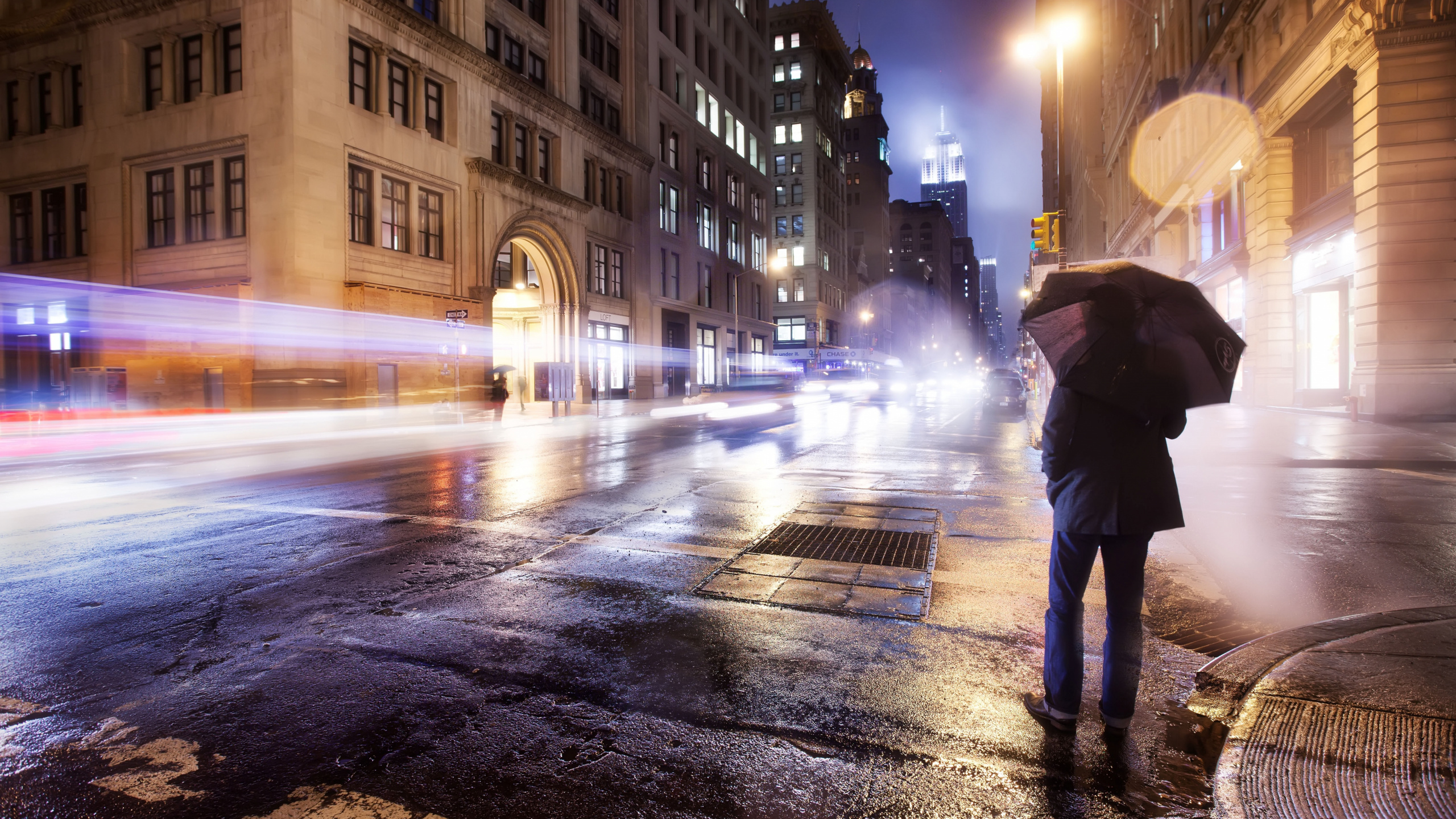 Persona Caminando en la Acera Durante la Noche. Wallpaper in 2560x1440 Resolution