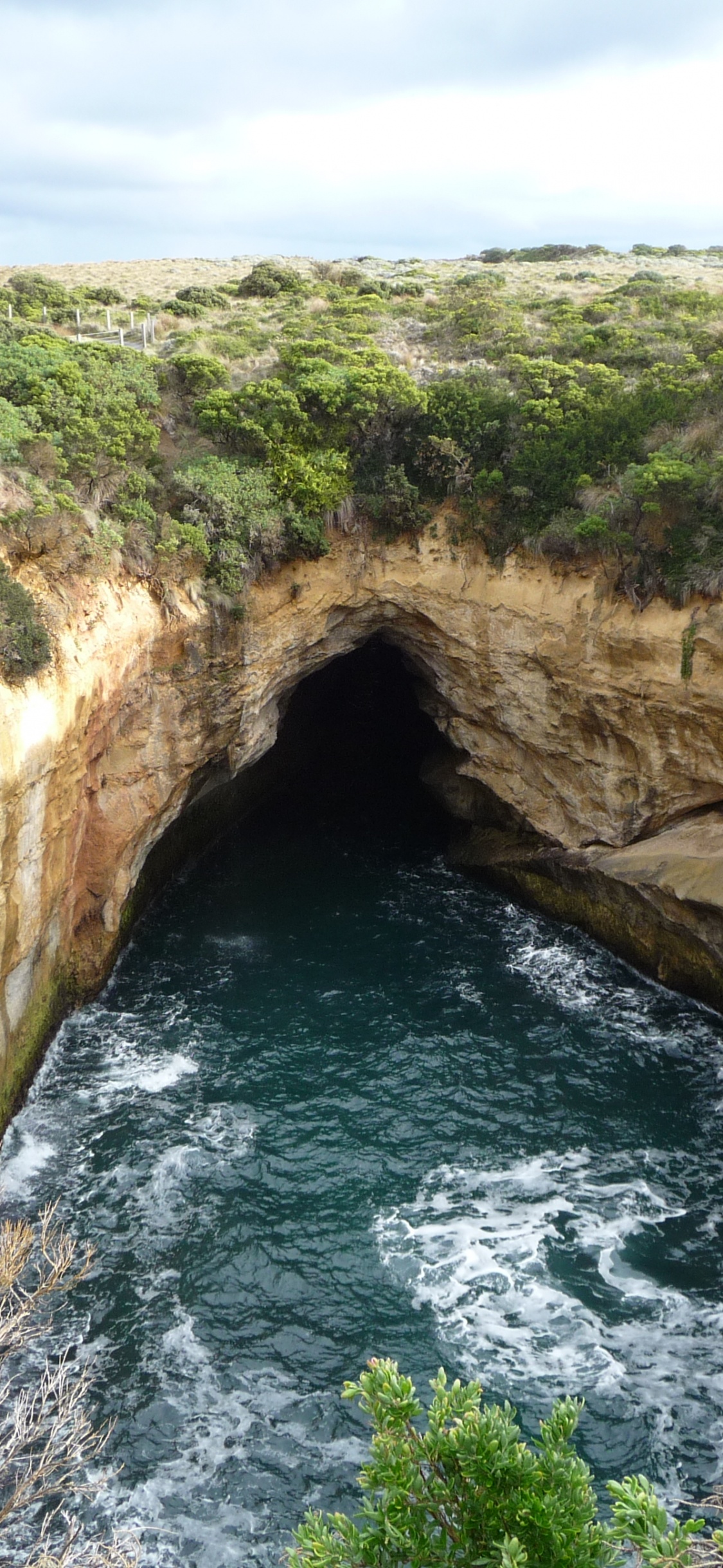 Formación de Roca Marrón Cerca Del Cuerpo de Agua Durante el Día.. Wallpaper in 1125x2436 Resolution