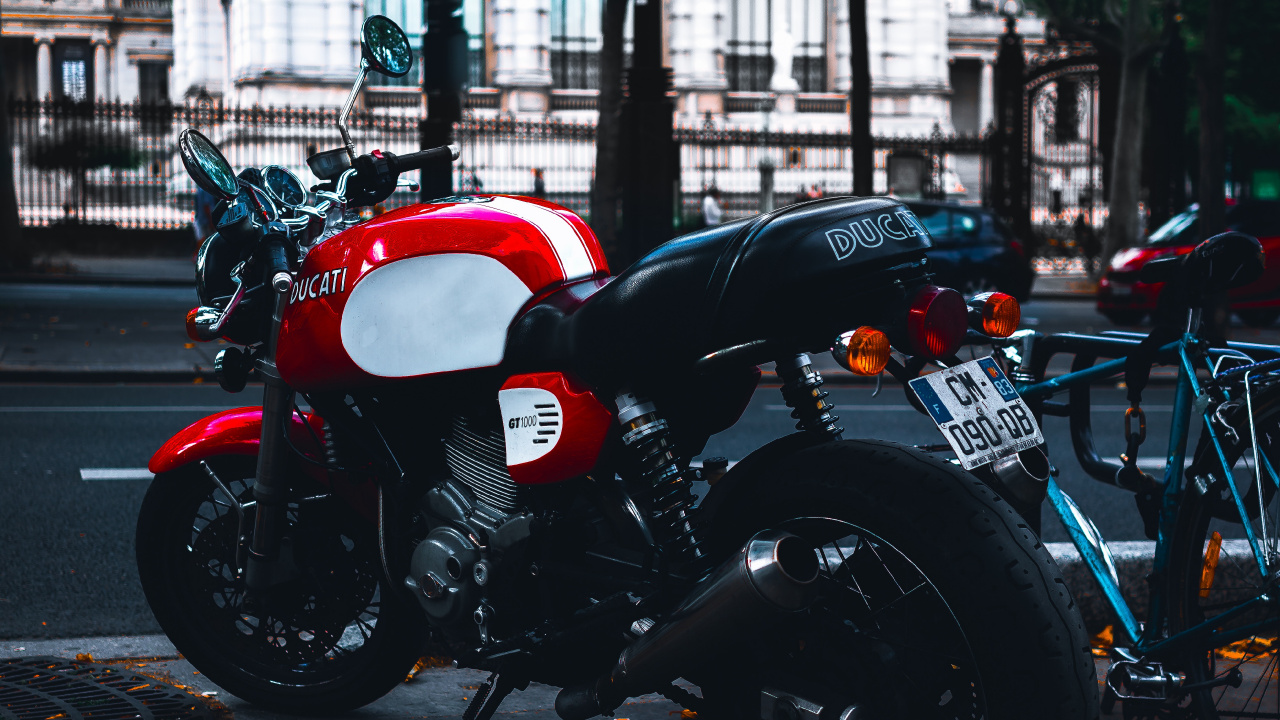Motocicleta Roja y Negra Estacionada en la Acera Durante el Día. Wallpaper in 1280x720 Resolution