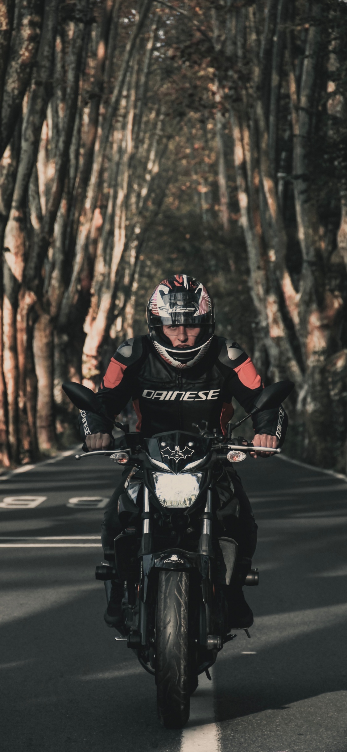 Homme en Costume de Moto Noir et Rouge Équitation Moto Sur Route Pendant la Journée. Wallpaper in 1125x2436 Resolution