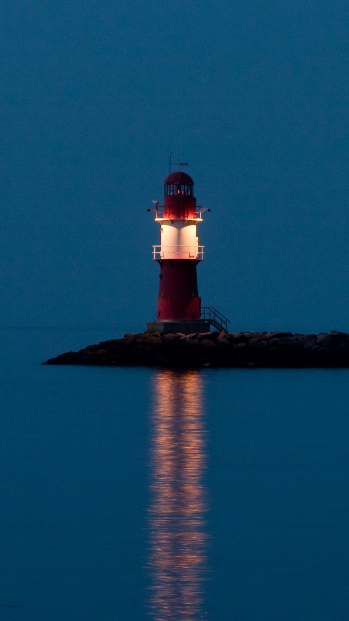 Faro Blanco y Rojo Cerca Del Cuerpo de Agua Durante la Noche.. Wallpaper in 720x1280 Resolution