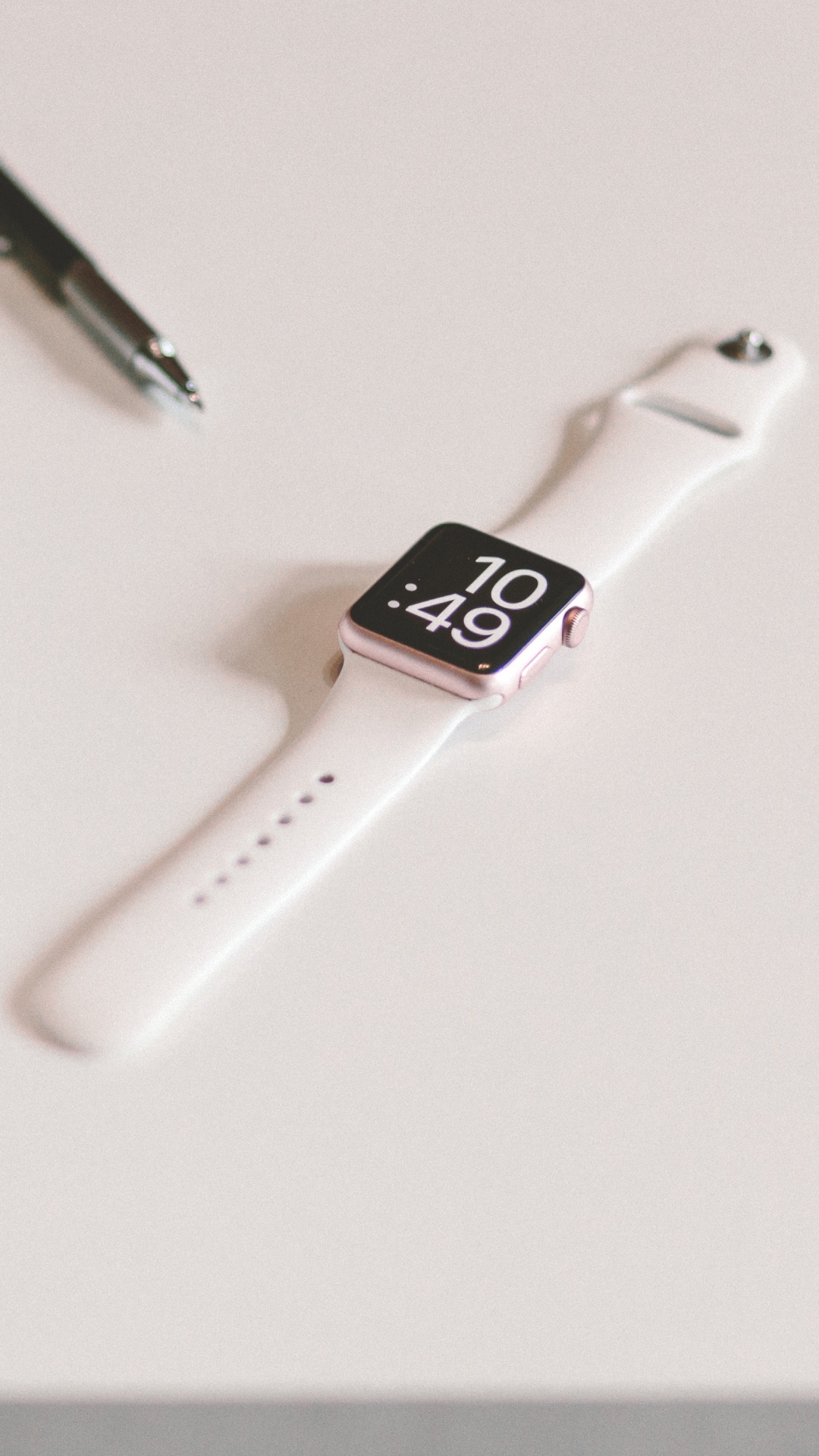 Silver Apple Watch With White Sport Band Beside Black Click Pen. Wallpaper in 1080x1920 Resolution
