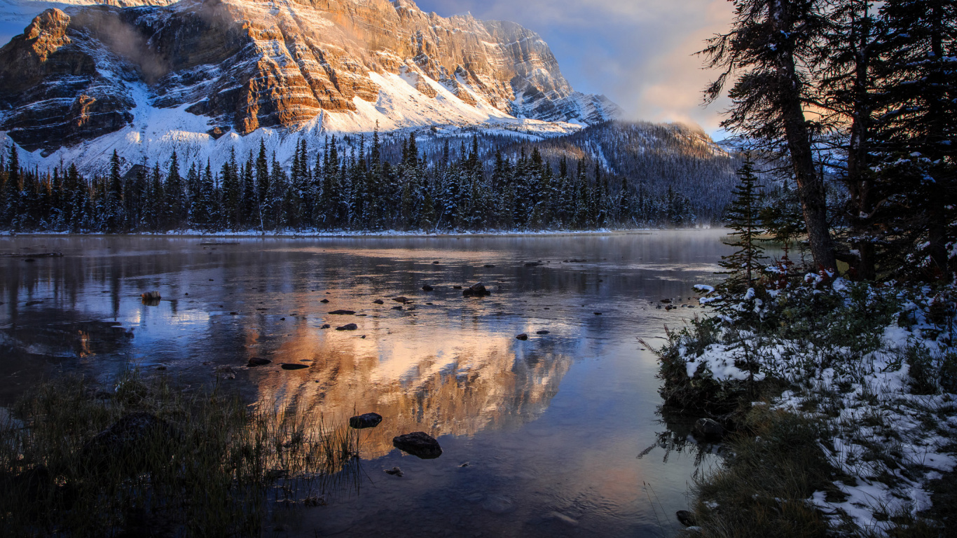 Lake Surrounded by Trees and Snow Covered Mountains. Wallpaper in 1366x768 Resolution