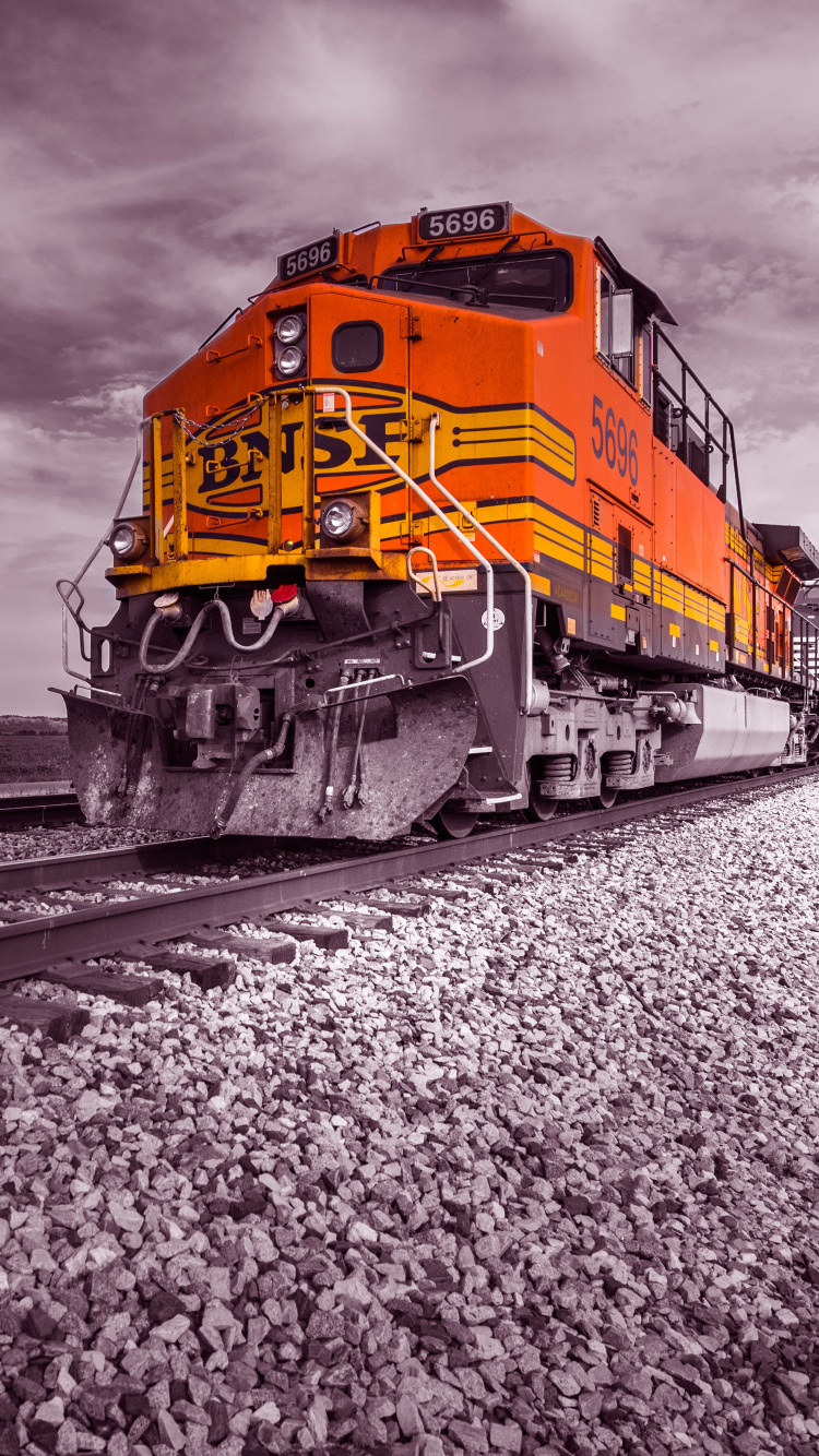 Train Jaune et Rouge Sur Les Voies Ferrées Sous Ciel Nuageux. Wallpaper in 750x1334 Resolution