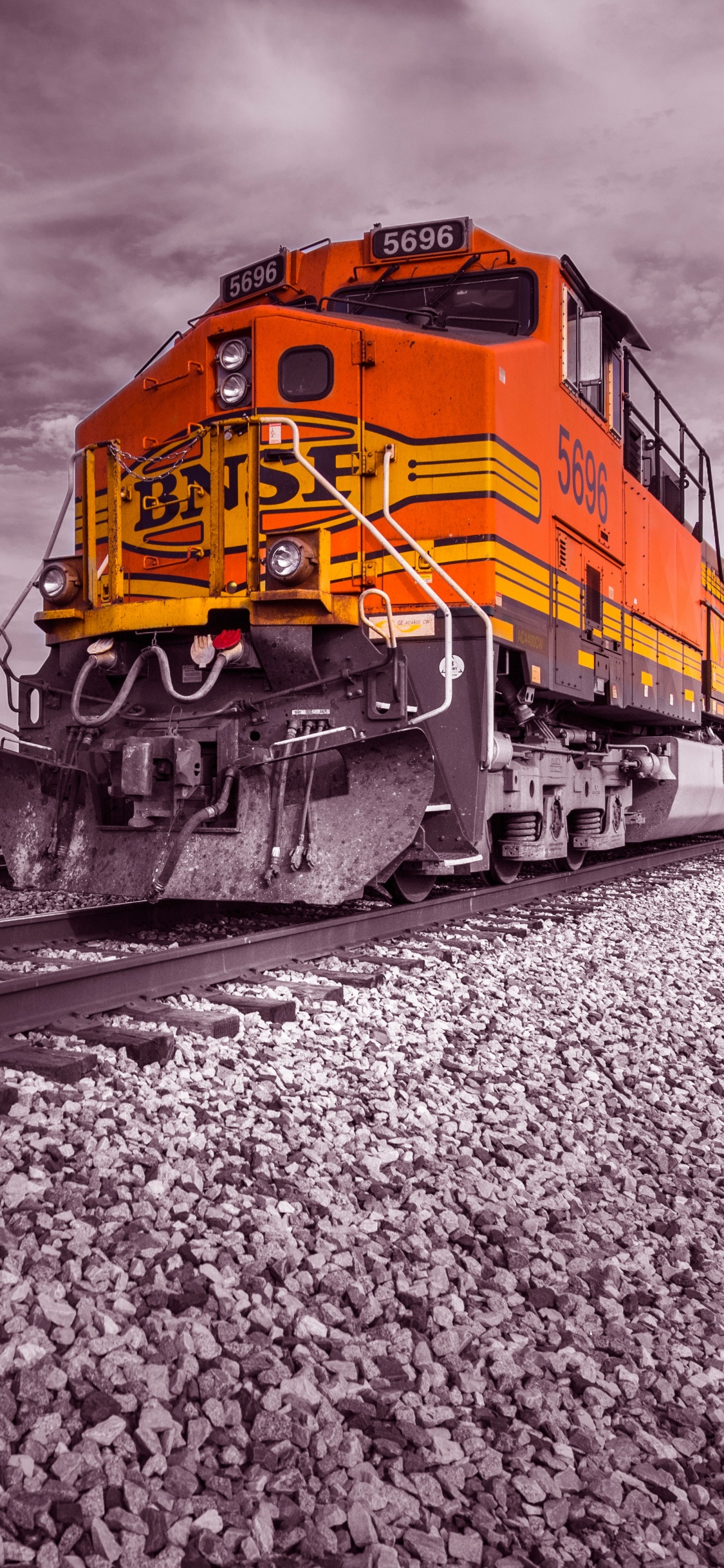 Yellow and Red Train on Rail Tracks Under Cloudy Sky. Wallpaper in 1125x2436 Resolution