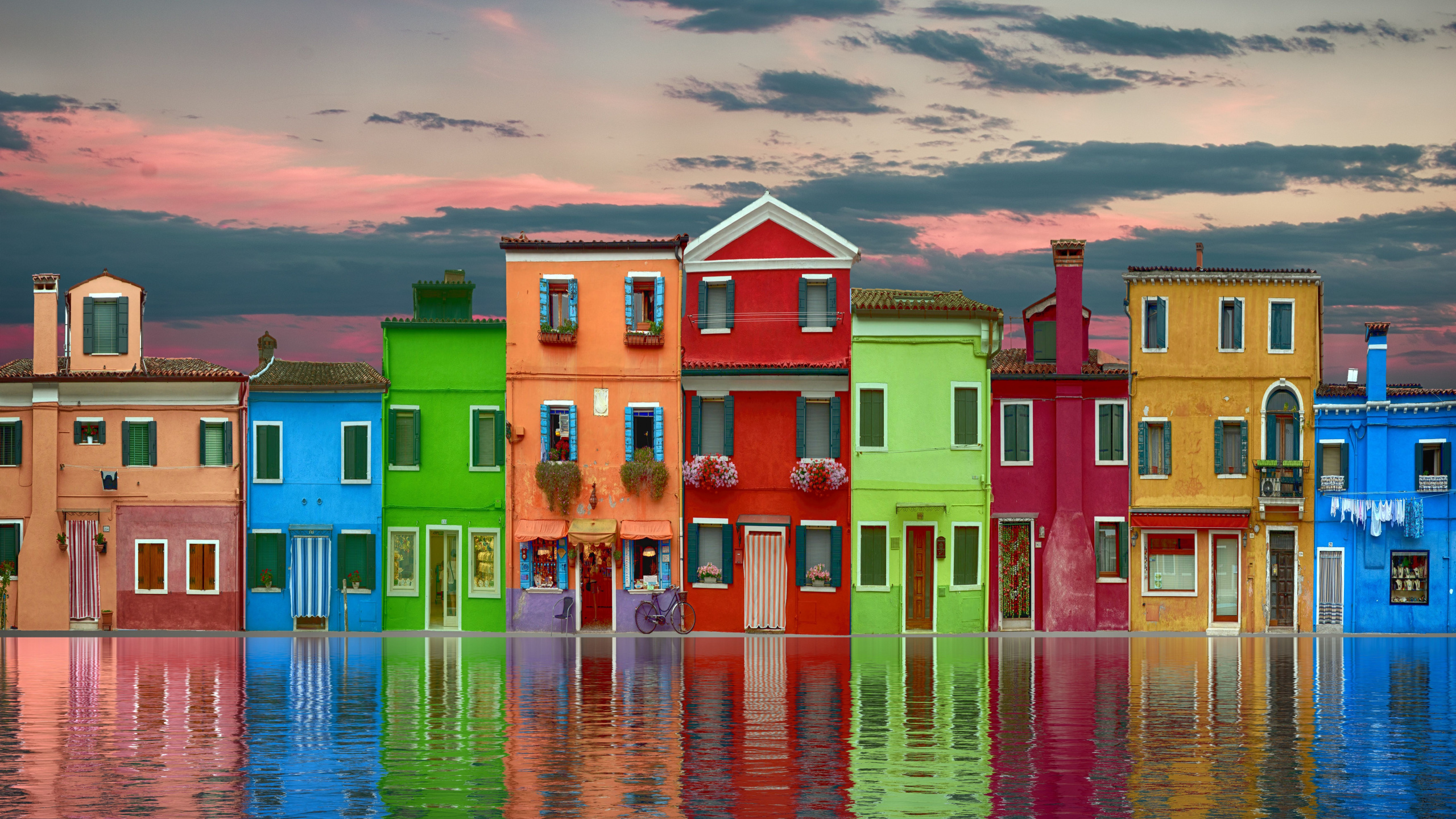 Rot-grünes Und Gelbes Betongebäude Neben Dem Gewässer Tagsüber. Wallpaper in 2560x1440 Resolution