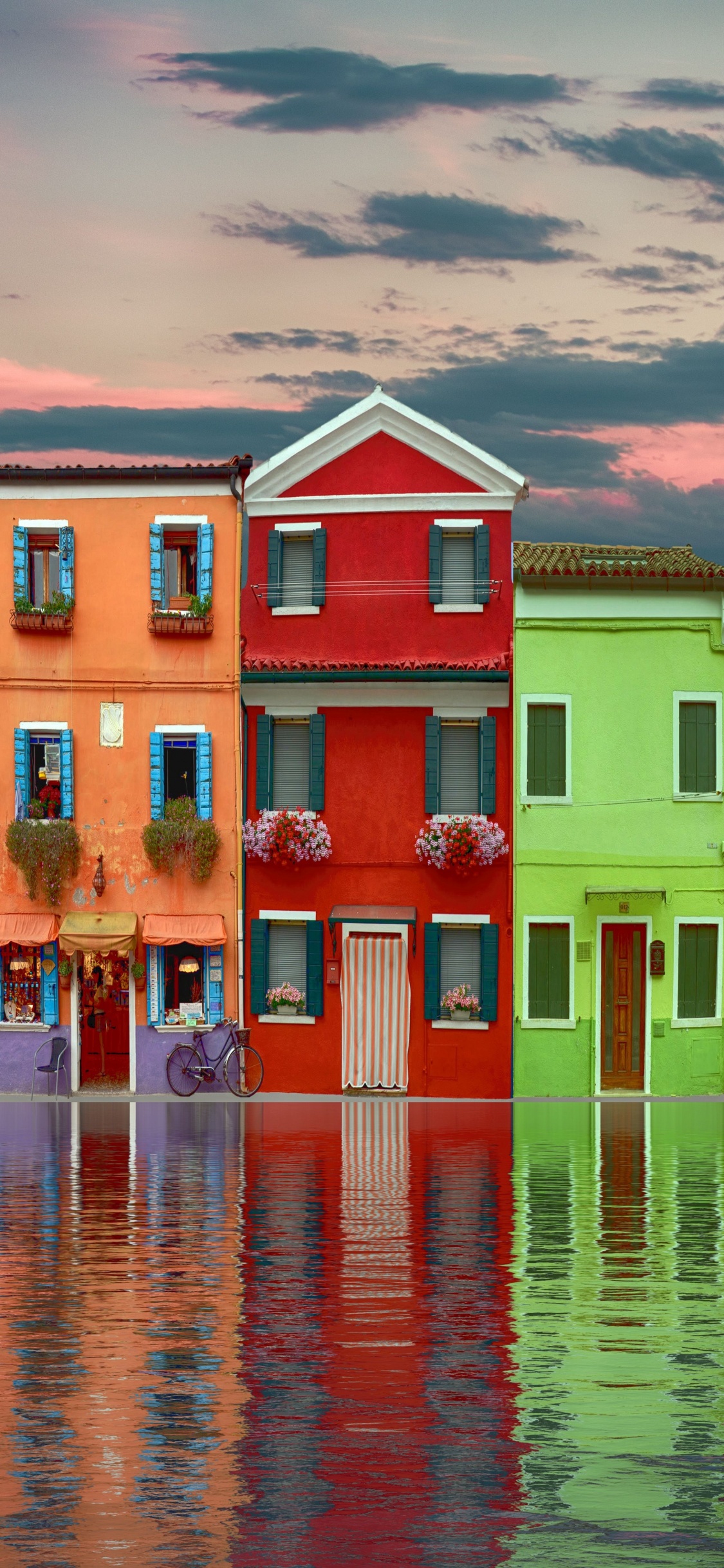 Red Green and Yellow Concrete Building Beside Body of Water During Daytime. Wallpaper in 1125x2436 Resolution