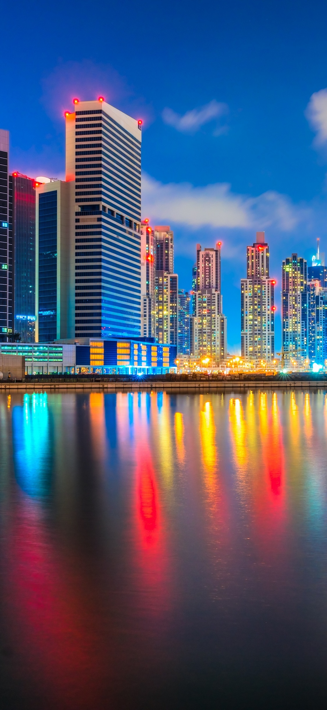 City Skyline Across Body of Water During Night Time. Wallpaper in 1125x2436 Resolution
