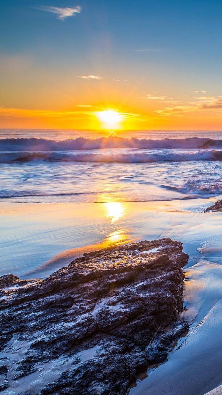 Orilla Rocosa Bajo un Cielo Azul Durante la Puesta de Sol. Wallpaper in 720x1280 Resolution