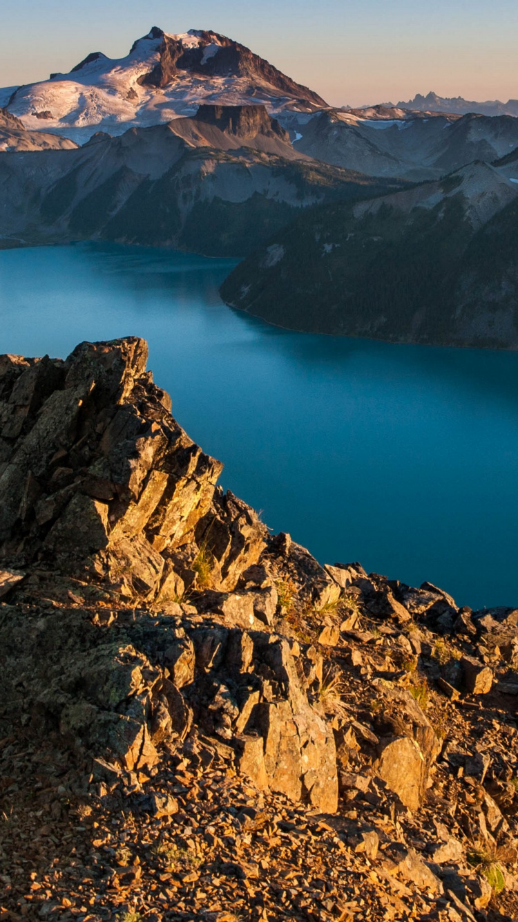 Brown Rocky Mountain Beside Blue Lake During Daytime. Wallpaper in 750x1334 Resolution