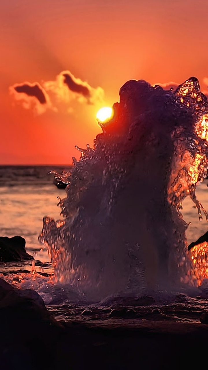 Silhouette of Person Standing on Rock Near Body of Water During Sunset. Wallpaper in 720x1280 Resolution