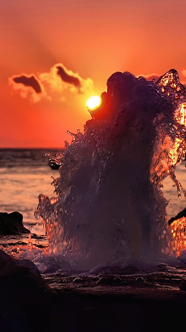 Silhouette of Person Standing on Rock Near Body of Water During Sunset. Wallpaper in 750x1334 Resolution