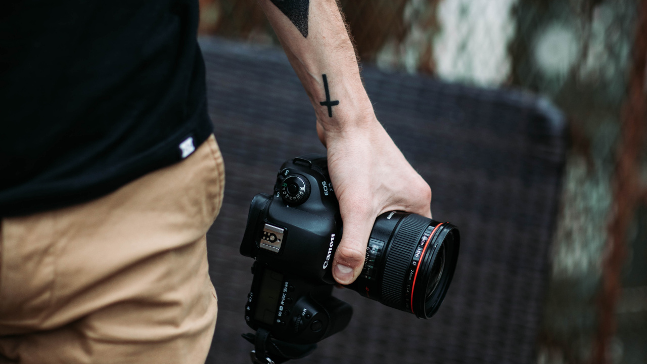 Man in Black Tank Top Holding Black Dslr Camera. Wallpaper in 1280x720 Resolution
