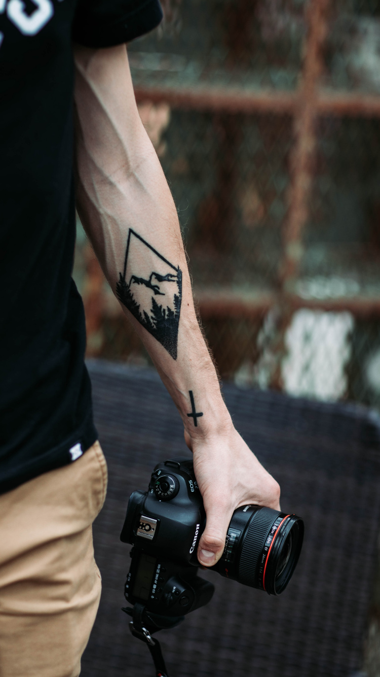 Man in Black Tank Top Holding Black Dslr Camera. Wallpaper in 750x1334 Resolution