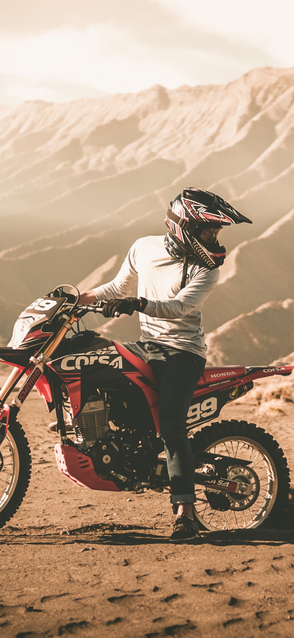 Man Riding Motocross Dirt Bike on Dirt Road During Daytime. Wallpaper in 1125x2436 Resolution