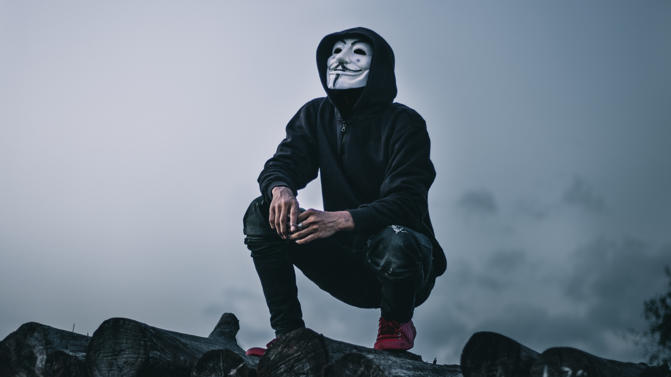 Man in Black Jacket Sitting on Rock. Wallpaper in 1366x768 Resolution