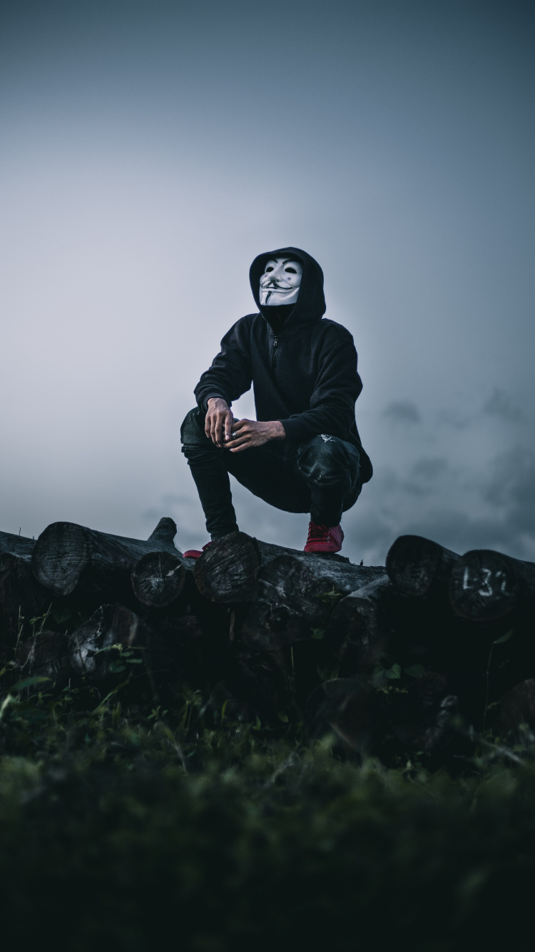 Hombre de Chaqueta Negra Sentado Sobre Una Roca. Wallpaper in 750x1334 Resolution