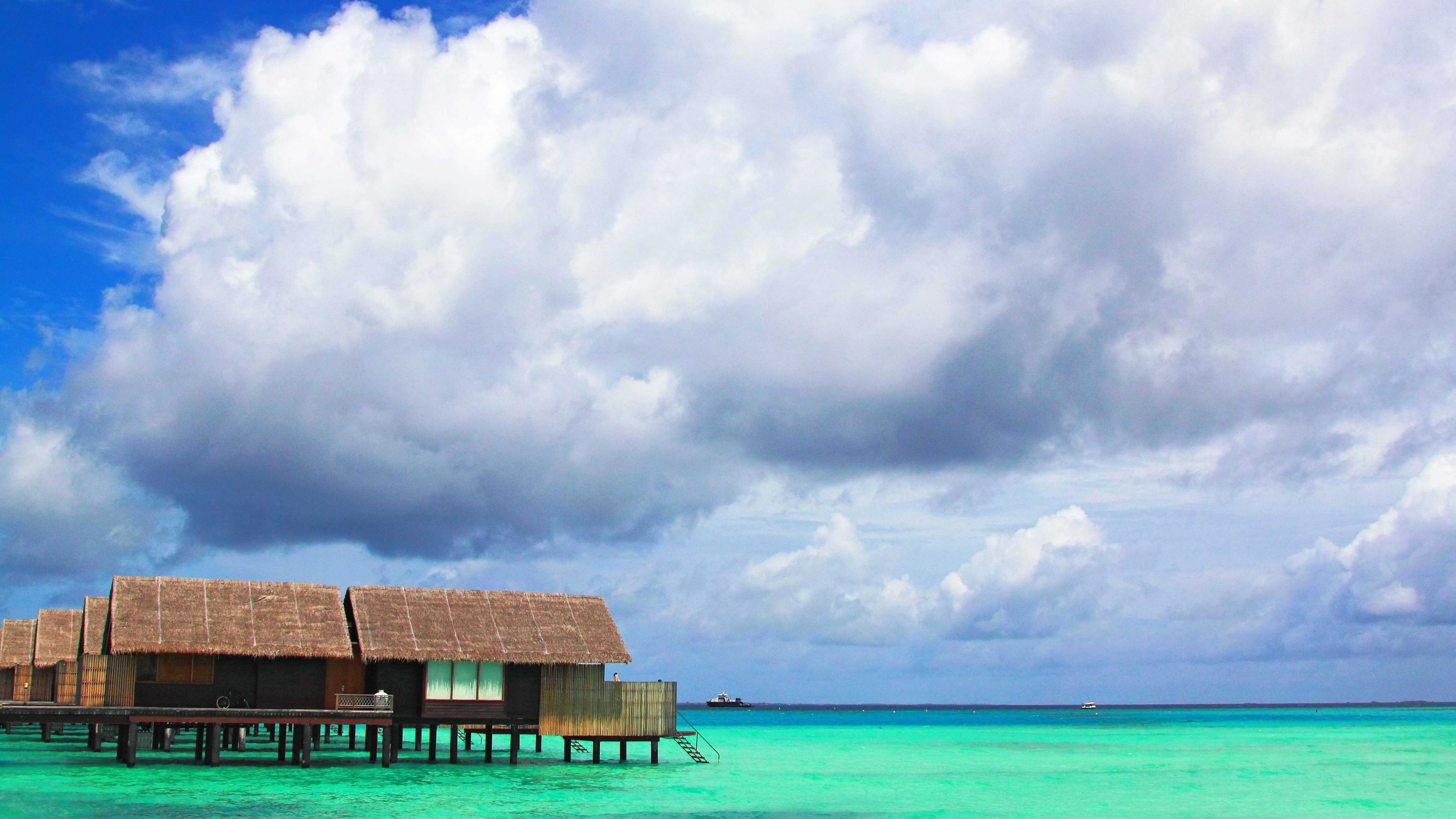 Braunes Holzhaus am Meer Unter Weißen Wolken Und Blauem Himmel Tagsüber During. Wallpaper in 3840x2160 Resolution