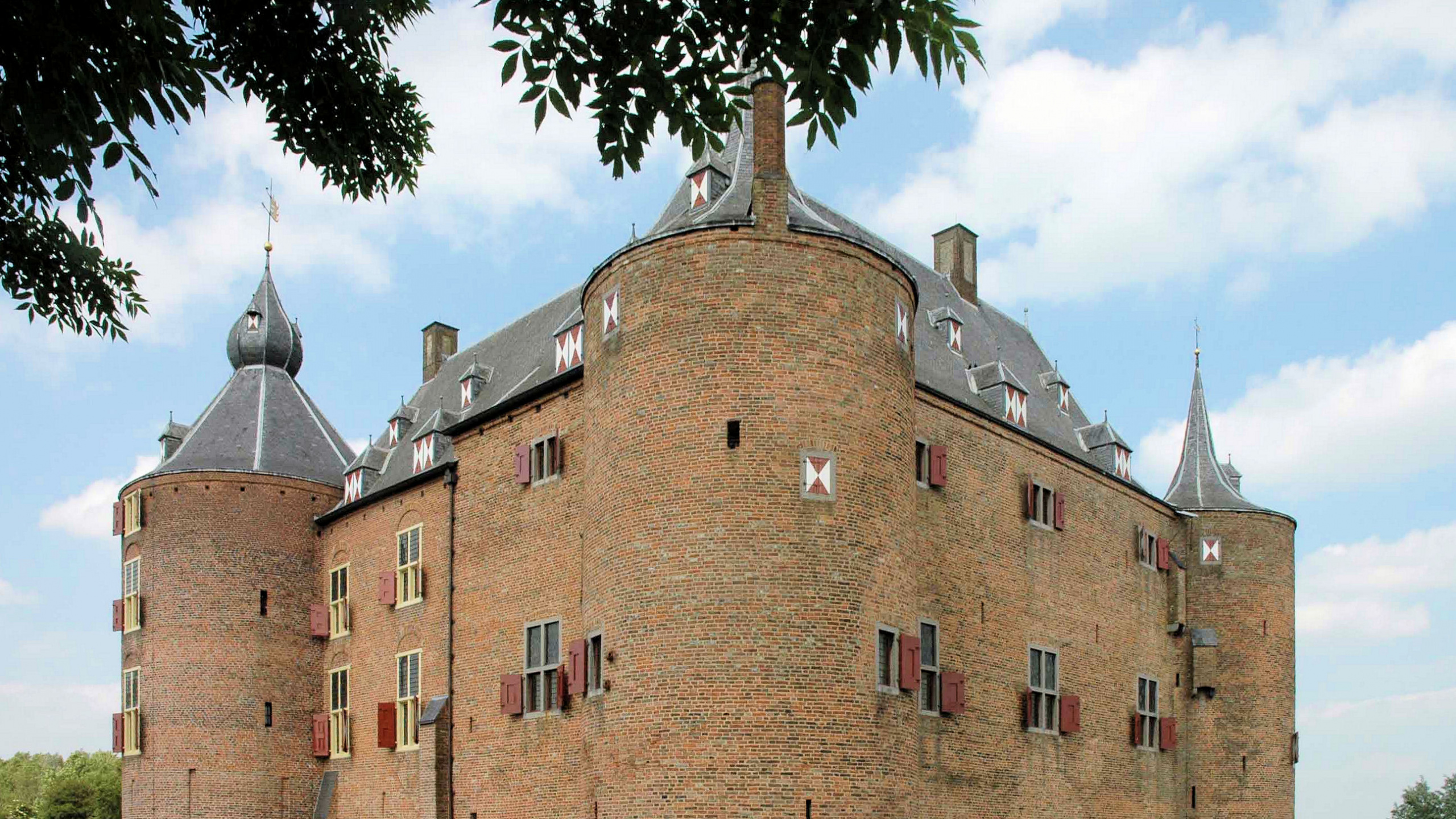 Edificio de Ladrillo Marrón Cerca de Árboles Verdes y Río Durante el Día. Wallpaper in 2560x1440 Resolution