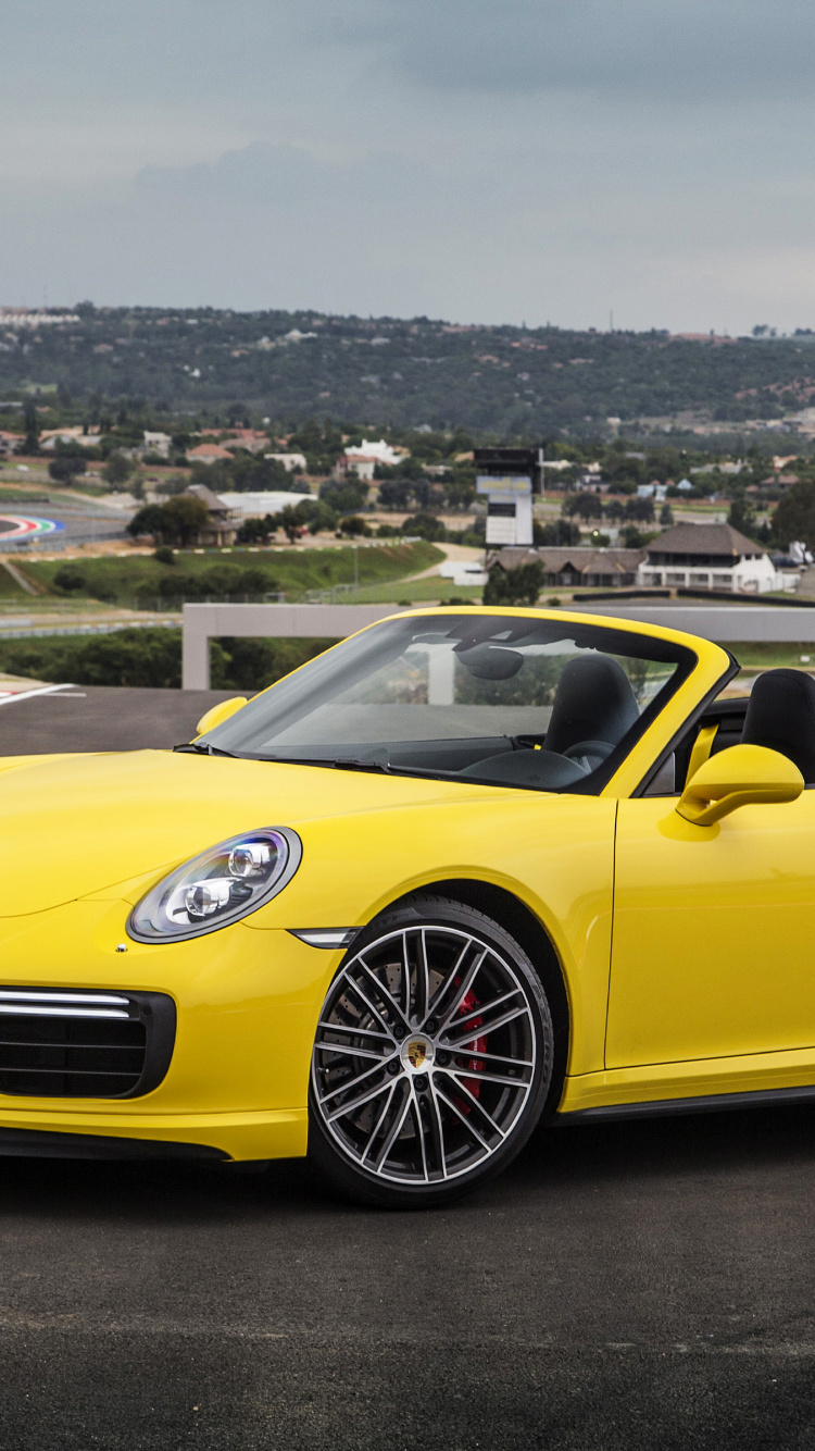 Gelber Porsche 911 Auf Einem Hügel Mit Blick Auf Stadtgebäude Tagsüber. Wallpaper in 750x1334 Resolution