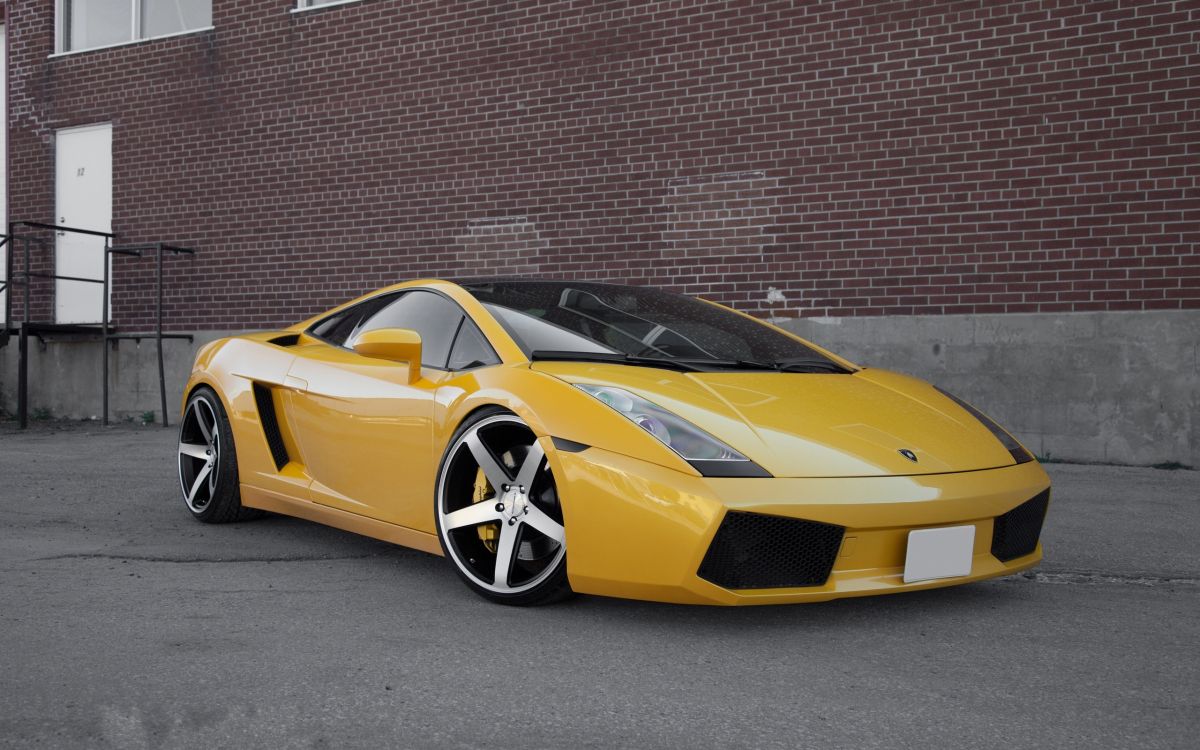 yellow lamborghini aventador parked beside brown brick wall