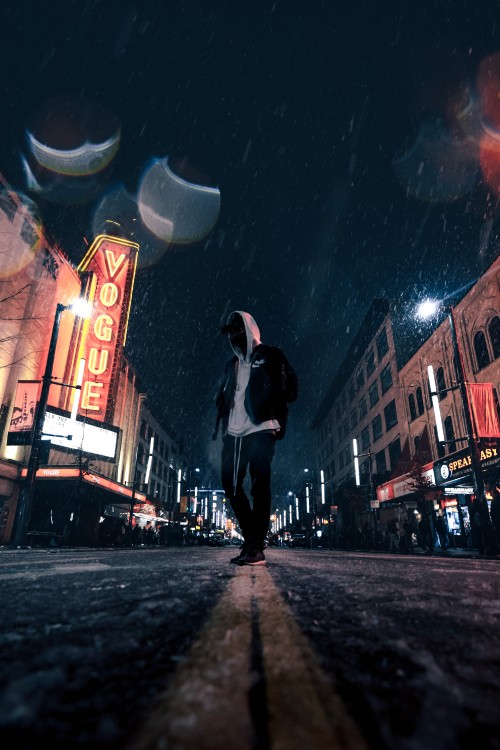 Image man in white shirt and black pants walking on street during night time