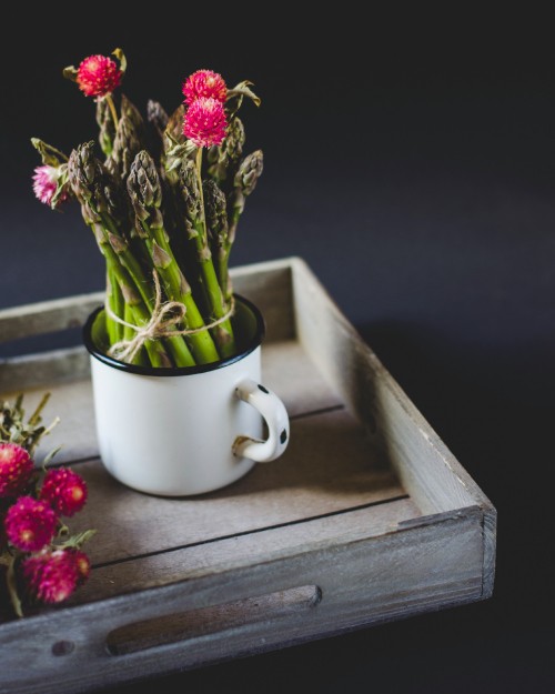 Image red flowers in white ceramic mug on brown wooden table