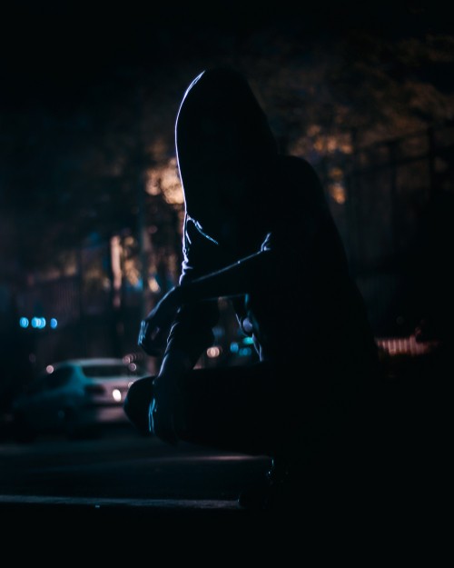 Image silhouette of person sitting on the street during night time