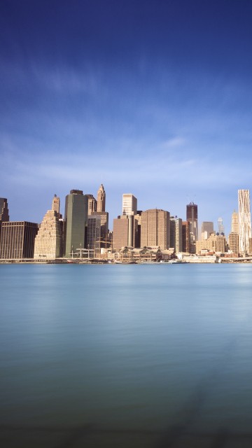 Image city skyline across body of water during daytime