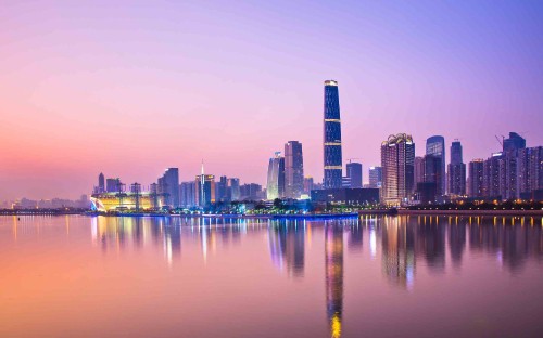 Image city skyline across body of water during night time