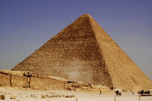 Image people walking on sand near pyramid during daytime