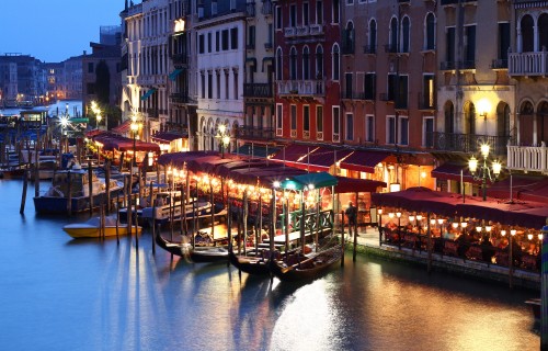 Image people riding on boat on river near buildings during night time