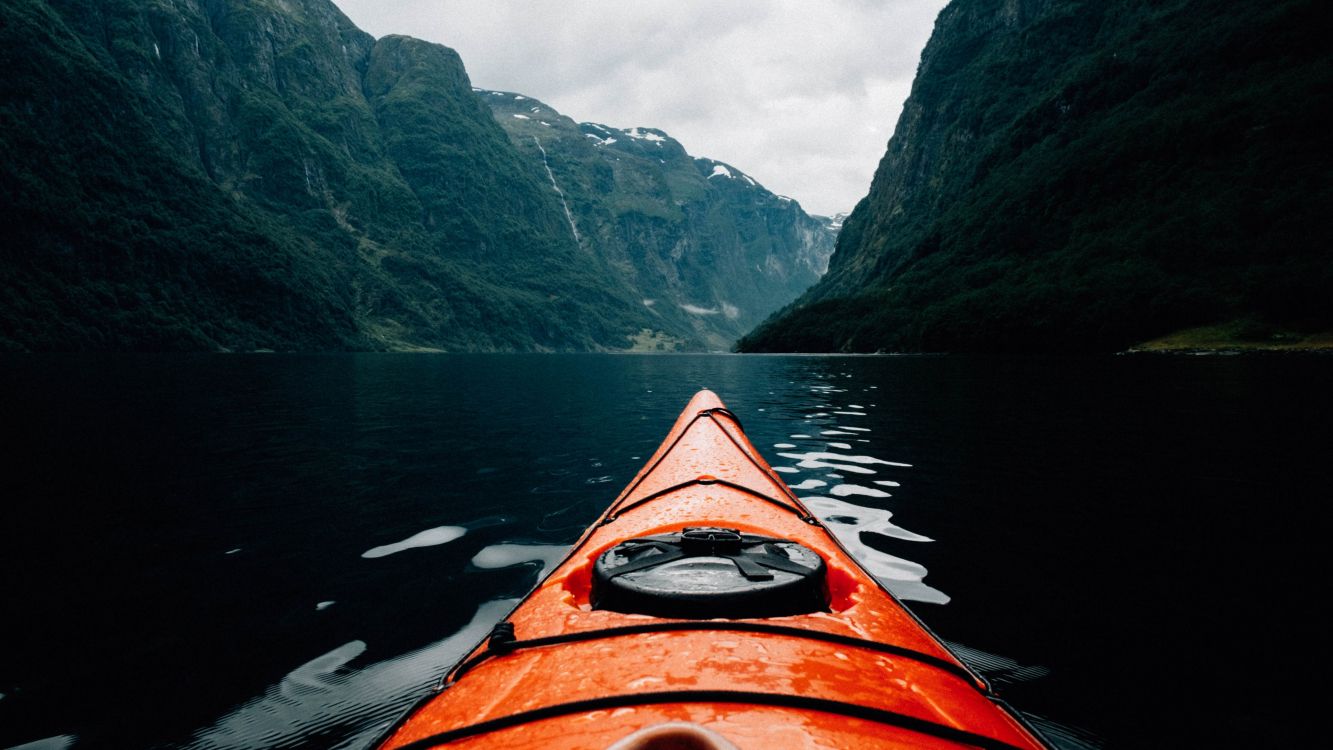 orange kayak on lake near mountain range