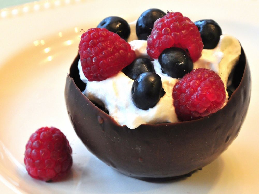 ice cream with raspberry and blueberry on white ceramic bowl