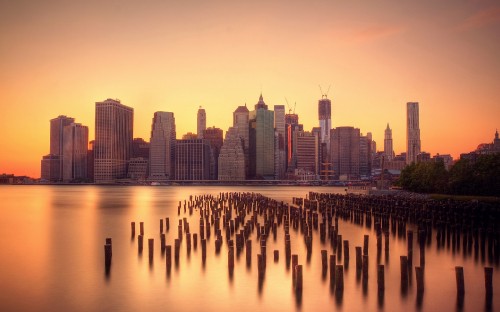Image city skyline across body of water during sunset