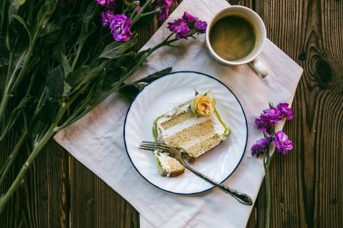 Image sliced cake on white ceramic plate beside silver fork