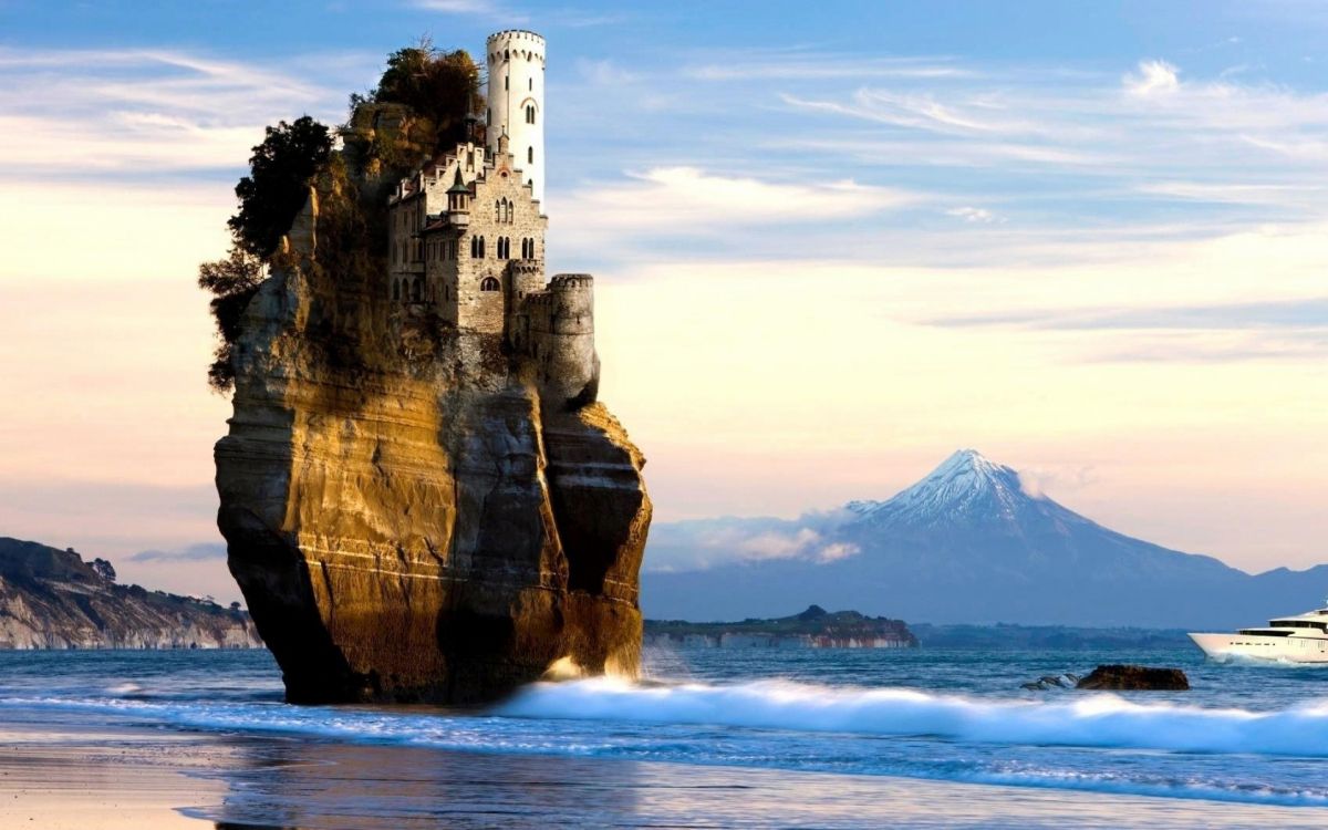 gray concrete building on top of brown rock formation near body of water during daytime